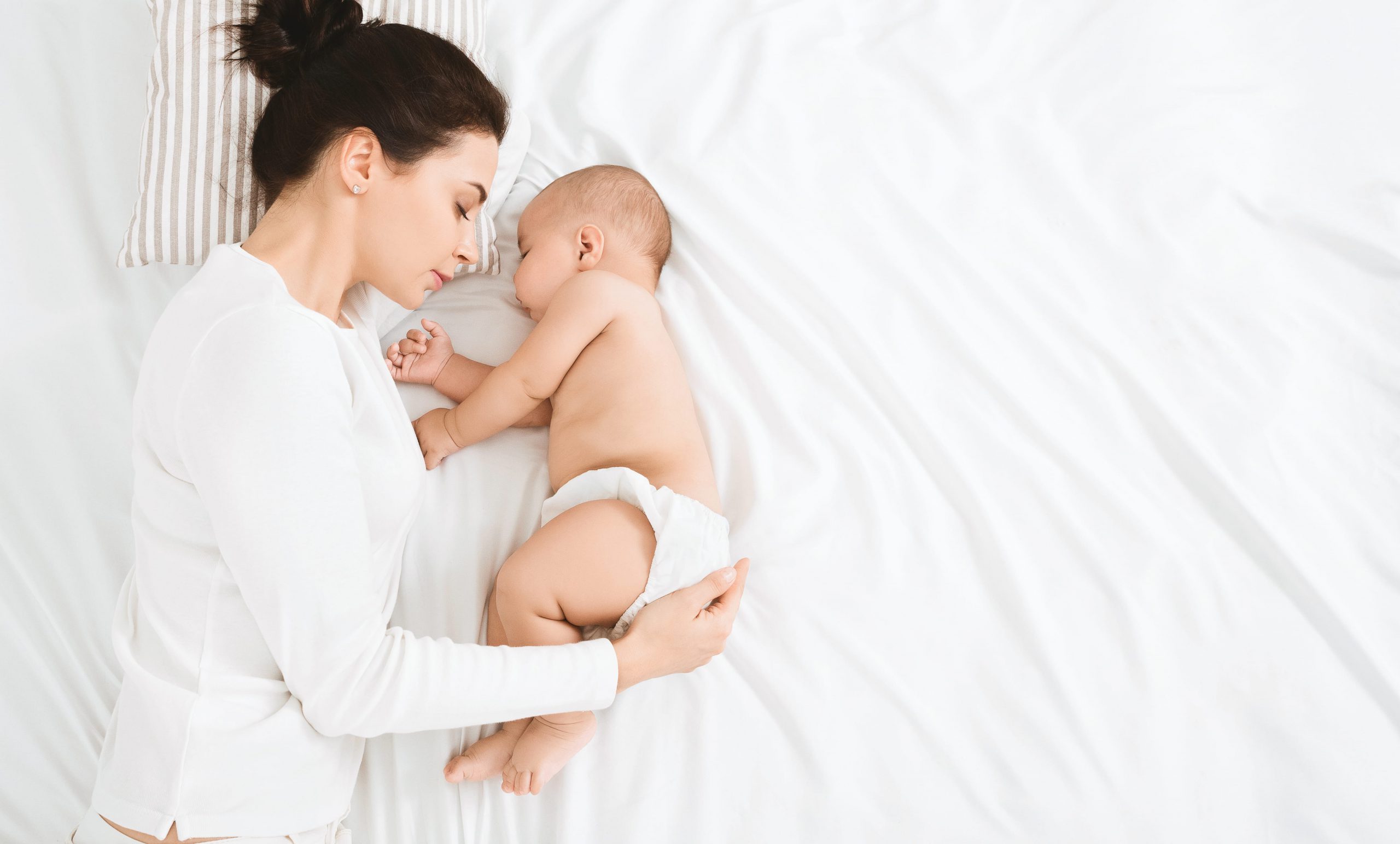 young mom and her cute baby sleeping in bed gb6jkys min scaled